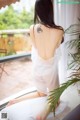 A woman sitting on a window sill with a tattoo on her back.