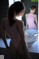 A woman in a pink bodysuit standing in front of a mirror.