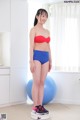 A woman in a red top and blue shorts standing on a scale.